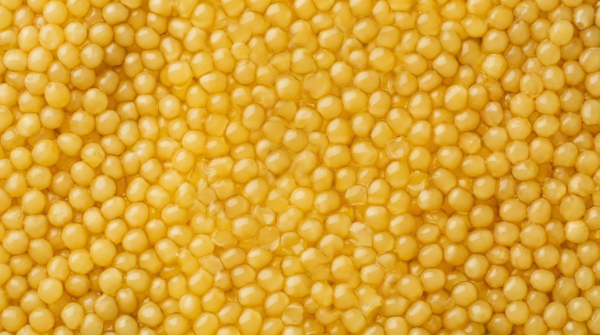 Caviar blanc servi dans une boîte ouverte, sans couvercle visible, avec grains clairs et cuillère en nacre