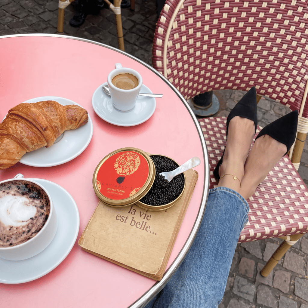 Boîte ouverte de Caviar Baeri Impérial de France – Délicatesse Caviarly’s sur une table de café avec croissant et café
